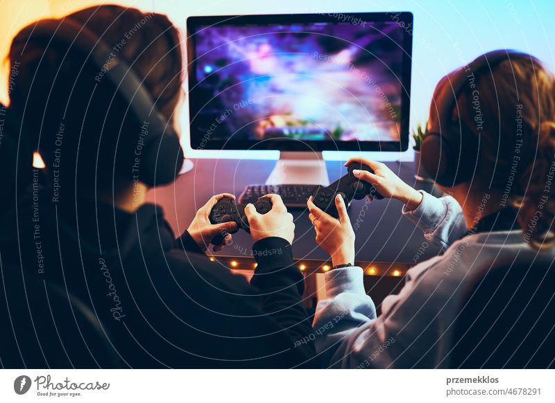 Friends playing video game at home. Gamers playing online in dark room lit by neon lights. Competition and having fun friends gaming competition gamer