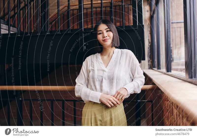 Portrait of confident mid adult Chinese woman smiling and leaning on railing, looking at camera asian business portrait one chinese confidence leadership PC2022
