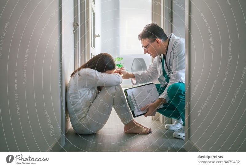 Psychiatrist trying to help with empathy a patient with mental disorder who refuses help psychiatrist woman mental health center hospital sitting floor pijama