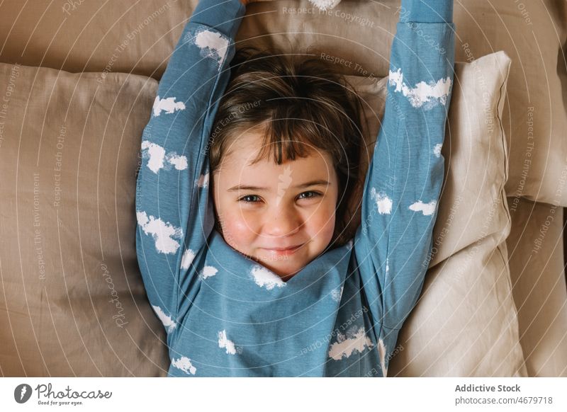 Cheerful girl in pajama lying on bed kid childhood bedroom morning domestic bed time cozy apartment adorable flat cute home residential nightwear dwell light