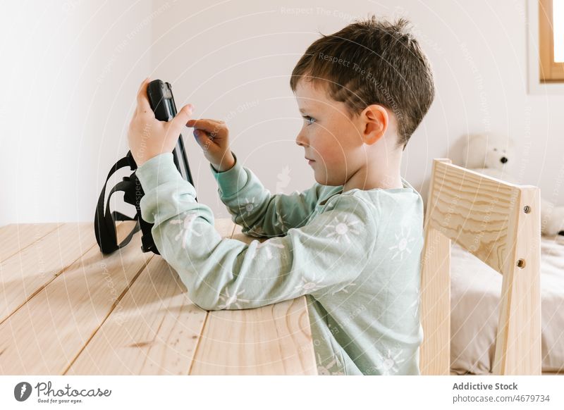 Cute boy in pajama watching video on tablet kid childhood cartoon pastime morning domestic room apartment adorable flat cute home residential nightwear dwell