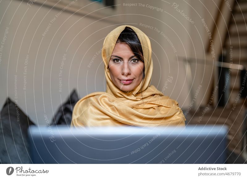 Muslim freelancer using laptop at home woman remote project online data tradition female smart adult ethnic muslim islam computer culture work distance telework