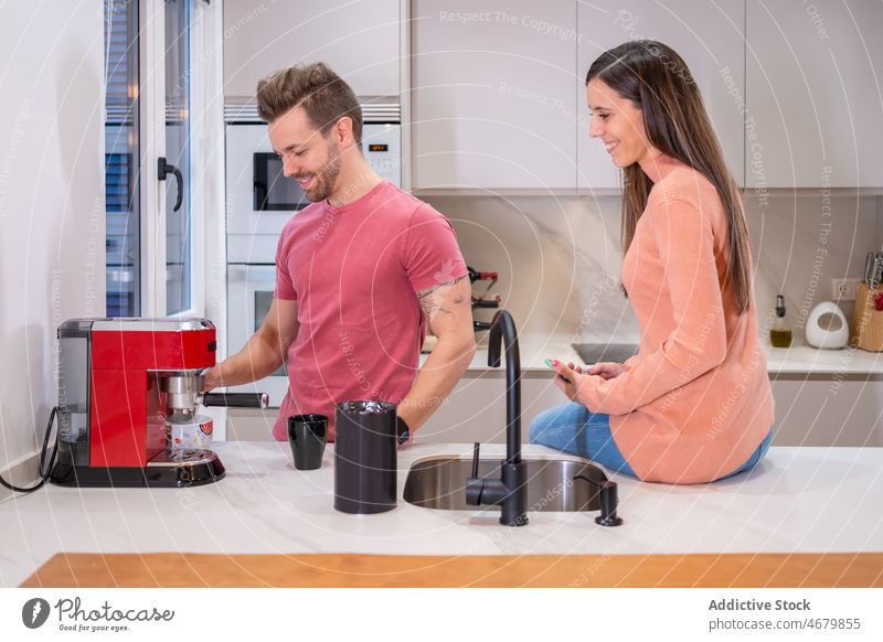 Cheerful couple preparing coffee in kitchen coffeemaker machine caffeine appliance kitchenware brew hot drink tasty prepare delicious man woman boyfriend