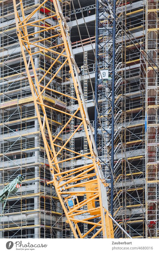 Facade of a construction site, in front of it boom of a crane Construction site Scaffolding Grating Crane Yellow Redevelop Structures and shapes Modernization