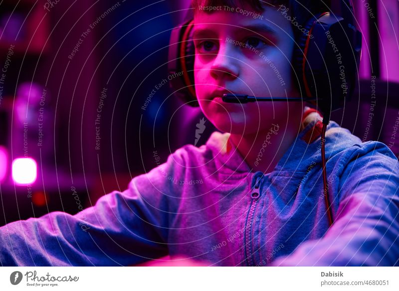 Boy plays computer game at home, gaming addiction portrait boy gamer workplace player cybersport headphones room video game dark online virtual entertainment