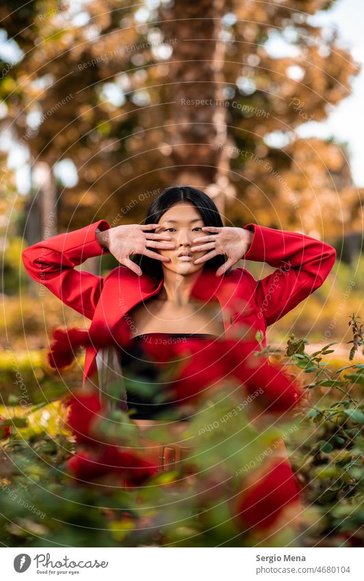 Art portrait of elegant east asian woman in red dress in garden Woman Elegant posing Garden East Asian Spain Red Suit flowers Park stylish Attractive Model