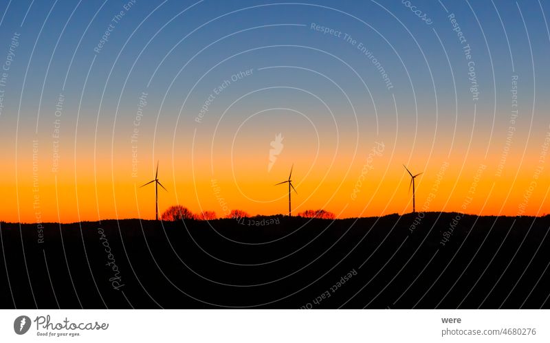 Silhouettes of three wind turbines against magnificent colored evening sky CO²-neutrality electromobility silhouettes Wind turbines Climate Neutral