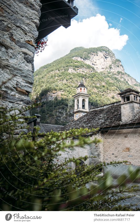 Church tower and old houses in front of mountain Village Ticino stone house Roof Fireside Mountain Clouds Facade