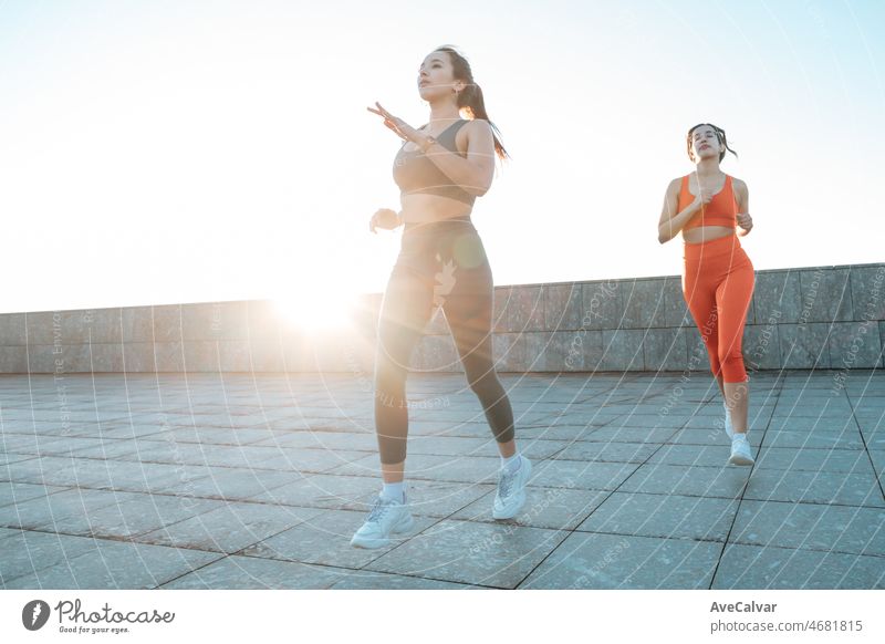 Two young multi cultural woman jogging on urban city train to lose weight before summer to get a defined body. Running and workout outdoors. Sunset scene with young athletes