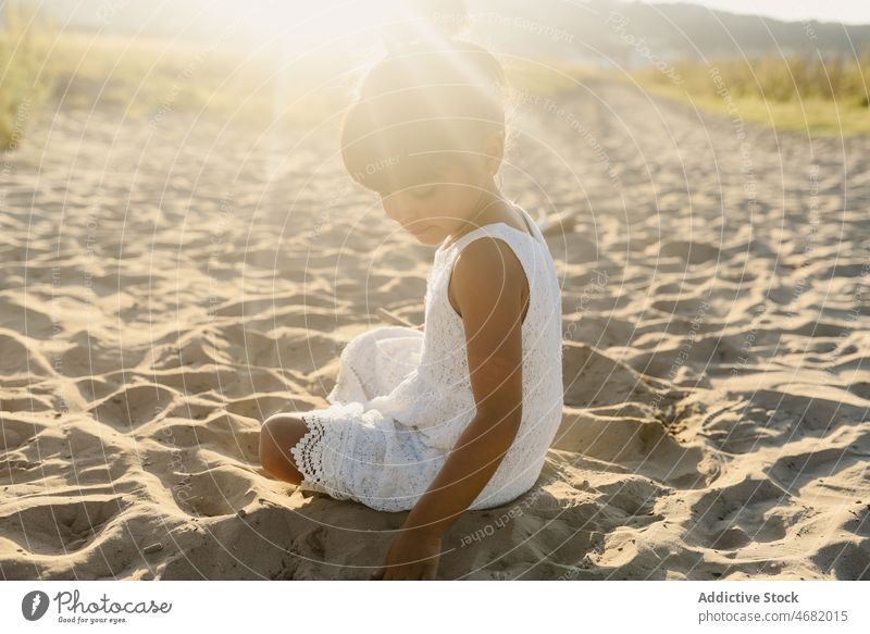 Little girl playing with sand kid beach summer happy adorable cute hispanic childhood joy friendly smile glad funny nature ethnic summertime innocent content