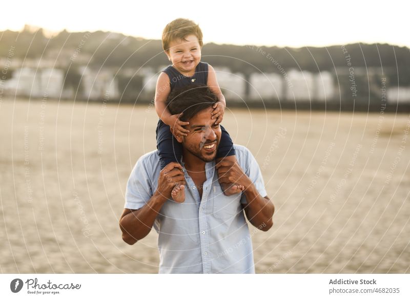 Happy Latin American man with boy on beach father son fatherhood child playful coast on shoulders childhood recreation laugh sand summer together happy nature