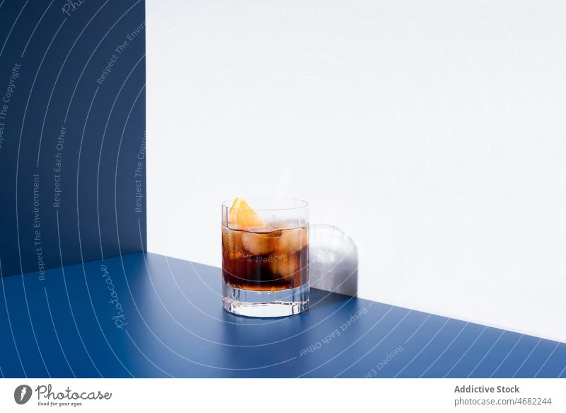 Red vermouth served in glass on blue and white background red alcohol cocktail orange beverage booze aperitif drink citrus portion fruit refreshment studio