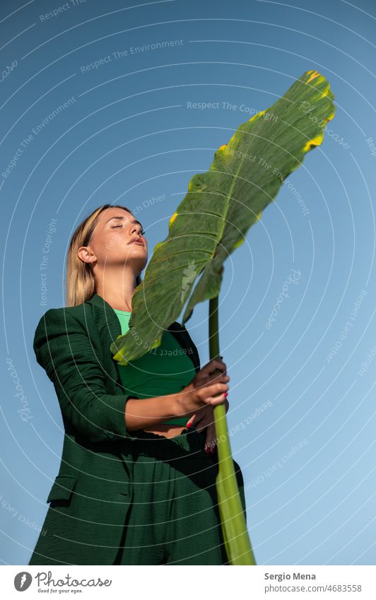 Fine art photography of an elegant Caucasian woman on the beach with a large green leaf artistic Artist Peace Water barefoot Spain Europe plant clear blue sky
