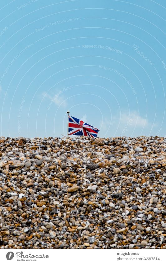 Union Jack flag flying above a pebble beach background blue brexit britain british coast coastal day east wittering england english national no people outdoors