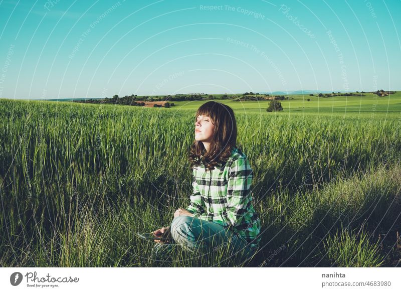 Young woman alone in a green field freedom nature freshness tranquility scene countryside lonely color spring springtime view full length breath pure purity