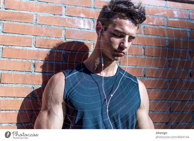 Male runner man taking a break from running training. sport person music earphones listening fitness lifestyle young wall outdoors sporty healthy male