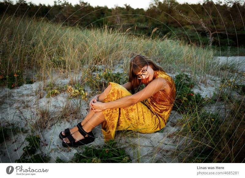On a perfect summer evening's golden hour a gorgeous brunette girl dressed in a golden outfit is getting comfy in golden dunes all by herself. It’s a majestic sunset that paints her pretty face in gold. And gold prices are jumping as well.
