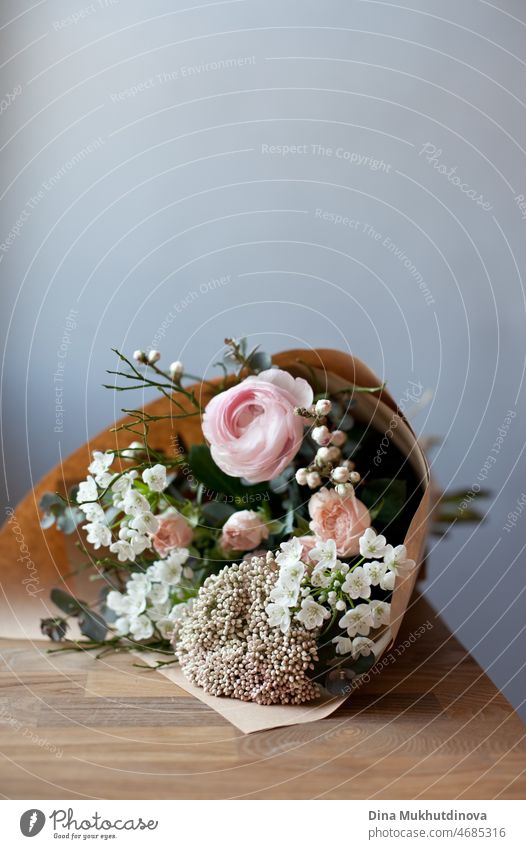 Bouquet of pink and white flowerson wooden table at flower shop. Floristics and selling flowers small business. Pink fresh spring floral background with copy space on top with light gray background.
