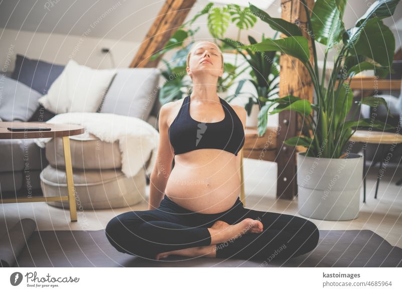 Young beautiful pregnant woman training yoga at home in her living room. Motherhood, pregnancy, healthy lifestyle and yoga concept mother baby care indoors