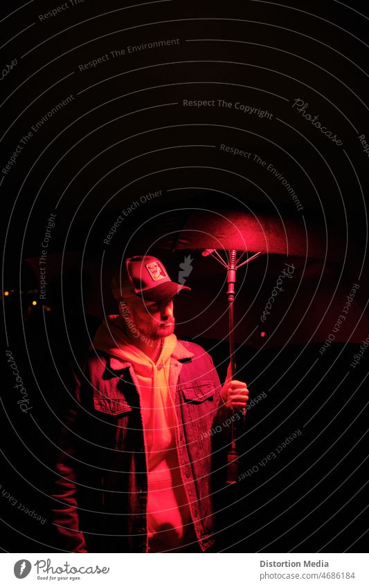 Young boy under an umbrella illuminated in red at night darkness dance silhouette fashion beauty black abstract light person party music dancing omnious cap