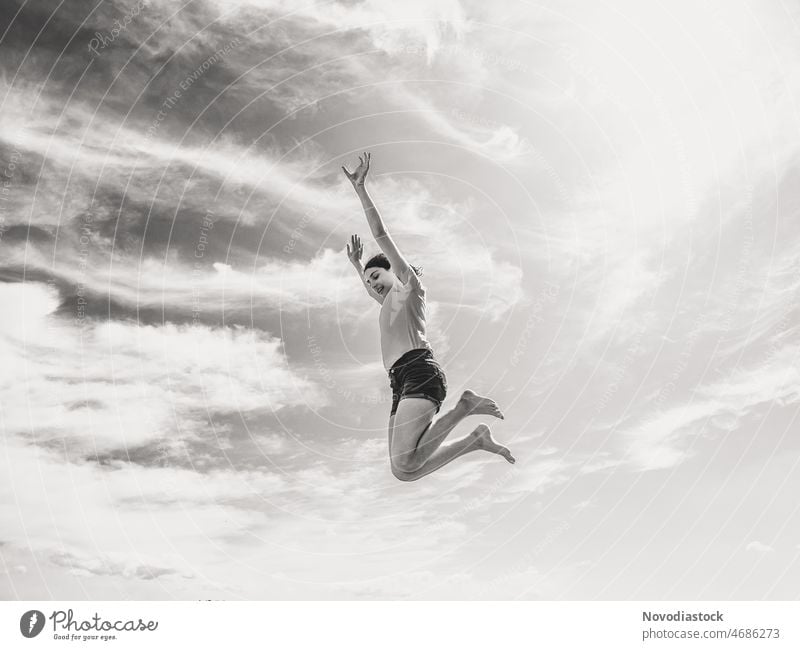 Black and white image of a teenage girl jumping high, isolated, sky is the background teenager Girl Jump black and white Black and white photography