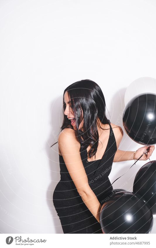 Attractive woman with black and white balloons birthday celebrate holiday style event festive smile fashion black dress feminine charming female happy occasion