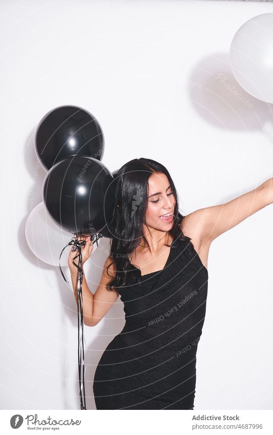 Attractive woman with black and white balloons birthday celebrate holiday style event festive smile fashion black dress eyes closed feminine charming female