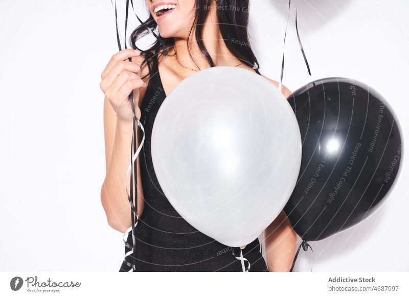 Anonymous attractive woman with black and white balloons birthday celebrate holiday style event festive smile fashion black dress feminine charming female happy