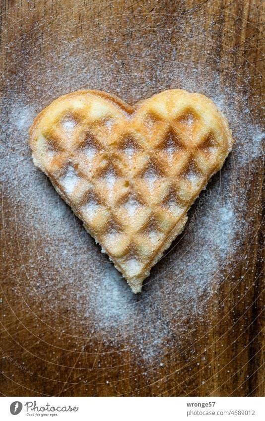 Homemade delicious waffle heart sprinkled with powdered sugar lies on a wooden board Waffle heart homemade self baked Delicious Crisp Confectioner`s sugar Food
