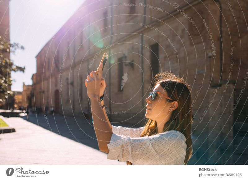 Young woman visiting an ancient city in spain taking a picture of a Salamanca monument with mobile phone one person discovery historic tourism tourist lifestyle