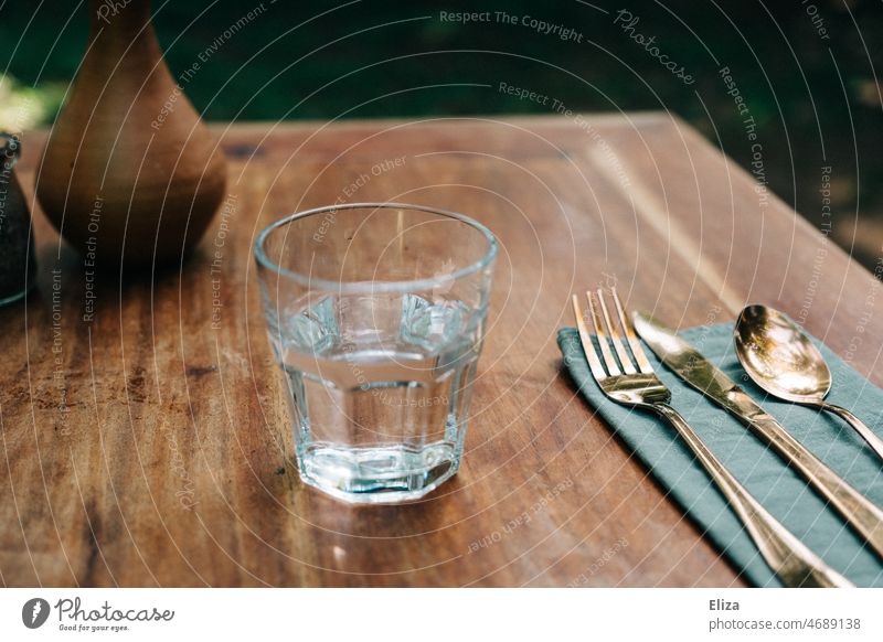 Water glass with cutlery on wooden table Tumbler Wooden table tap water Cutlery Table Glass Drinking water Thirst Restaurant covered golden drinking glass