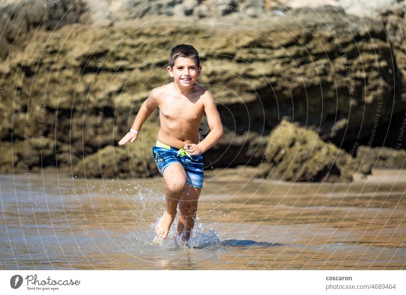 Little kid running on a rocky beach active activity baby blond boy cadiz cala del aceite caucasian child childhood coast conil cute energy enjoy enjoying fast