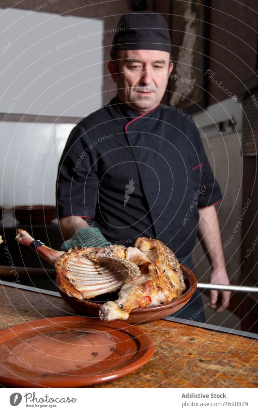 Chef with poultry in kitchen man chef cook meat restaurant work raw culinary food prepare bowl male job professional cuisine table furnace burn fire worker