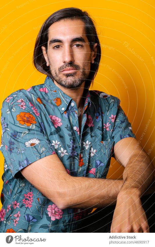 Man in yellow studio looking at camera man appearance mood beard portrait male unshaven color colorful light friendly carefree guy vivid style unemotional
