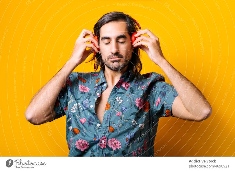 Man listening to music in headphones man meloman song sound hobby pastime portrait style wireless floral vivid male melody guy colorful modern entertain beard