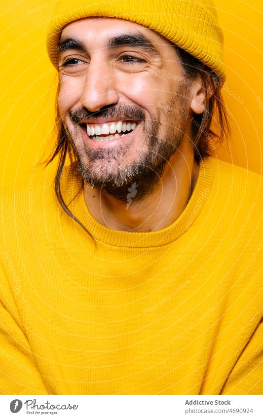 Cheerful man looking away in yellow studio carefree funny appearance silly mood playful beard portrait show male unshaven stare color gaze colorful light