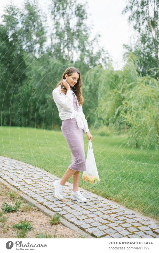 Stylish happy woman walking along a path in a Park and carrying fruit in a mesh bag model fun shorts femininity fit many net old fashioned outside pleasure