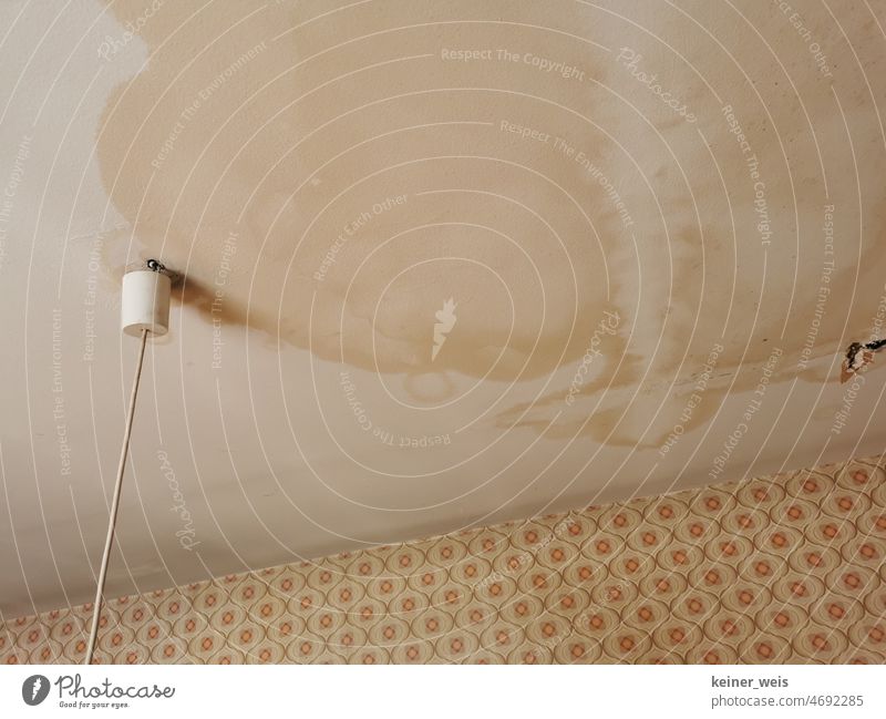 Water damage to the ceiling in a living room and old building with leaking roof living space Old building pipe rupture Roof Blanket Living room ceiling Lamp