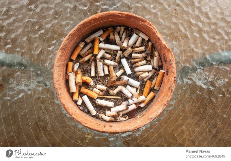 ashtray full of burnt cigarette butts, made of clay and on a glass table. addict addiction addictive anti-smoking ashtray cigarettes cancer closeup concept