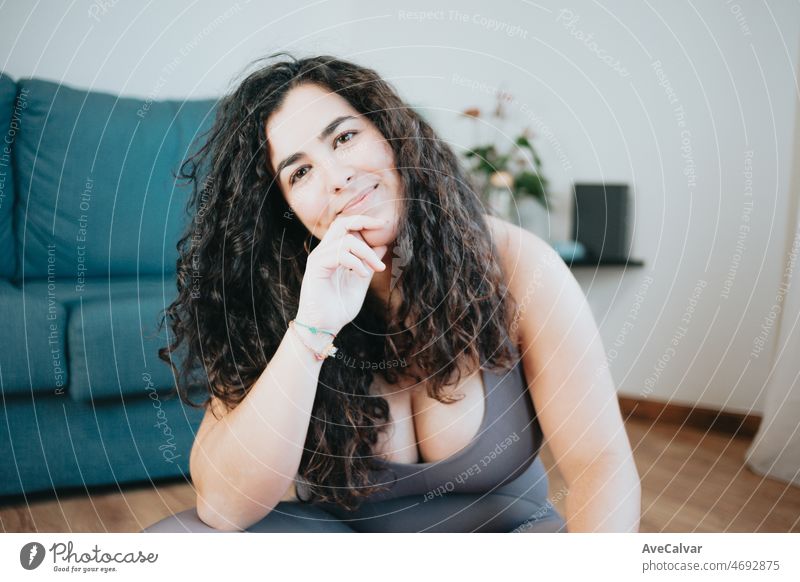 Super happy plus size curly woman smiling to camera portrait during a exercise session at home to lose weight. Training clothes. Getting fit for the summer concept.Beach body preparation, healthy life