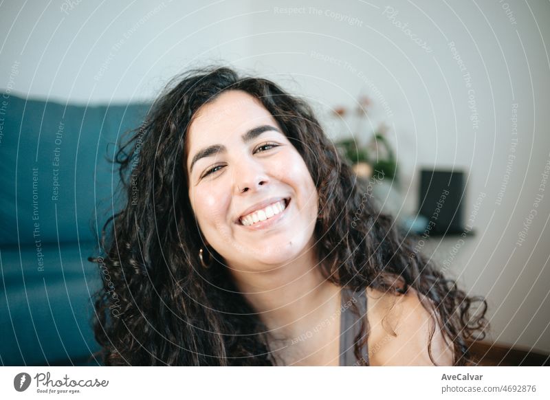 Close up of a happy plus size curly woman smiling to camera portrait during a exercise session at home to lose weight. Training clothes. Getting fit for the summer concept.Beach body preparation