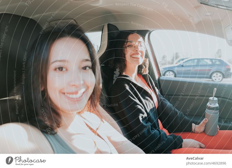 Two woman friends inside a car dressed in sport clothes while getting at the gym to workout. Training losing weight with friends together smiling to camera happy. African arab people doing exercise.
