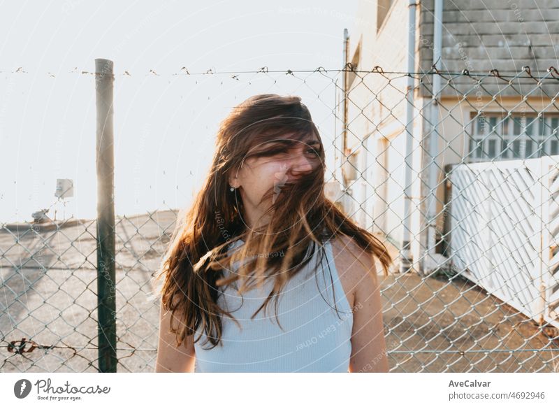 Frontal portrait of a young long hair woman waving his hair during the sunset, face covered in hair. Freedom, liberty and future is young concept. Outdoors lifestyle on social network. trendy gen z.
