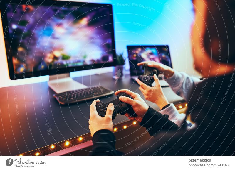 Friends playing video game at home. Gamers playing online in dark room lit  by neon lights. Competition and having fun - a Royalty Free Stock Photo  from Photocase