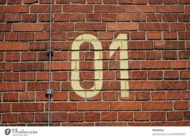 Yellowed large numbers as a marker on an old reddish brown brick wall in summer in the Klassikstadt in the Fechenheim district of Frankfurt am Main in the German state of Hesse