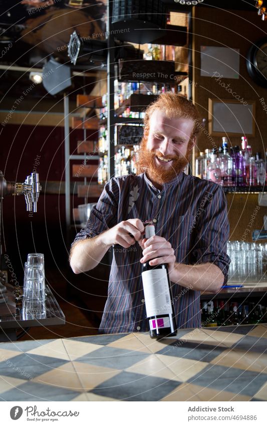 Bearded bartender opening wine bottle man alcohol aperitif beverage work drink barkeeper barman male professional content occupation counter workplace glad