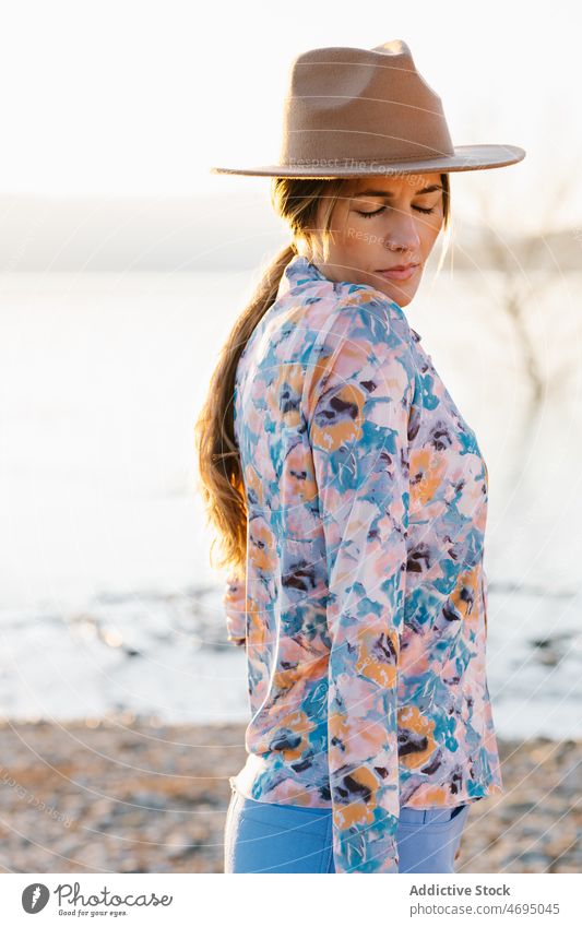 Enigmatic woman in hat on beach style water river nature enigmatic feminine summer eyes closed countryside coast shore sensitive female headwear headdress