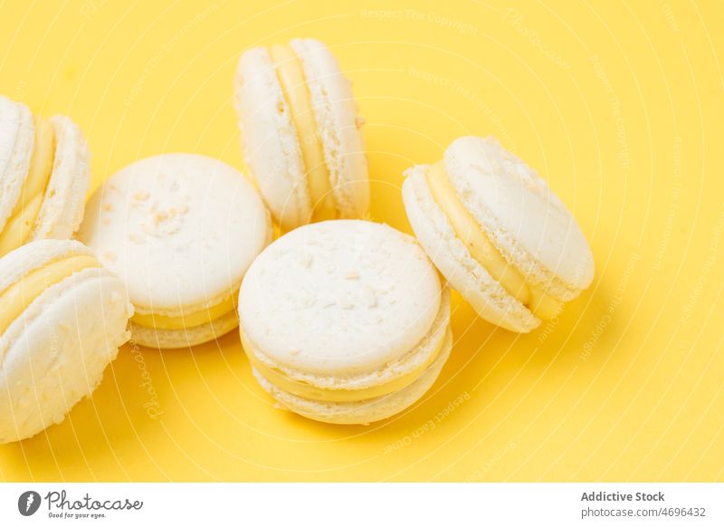 Pile of vanilla macarons on yellow background white dessert sweet confection confectionery indulge treat food flavor fresh tasty delicious yummy appetizing