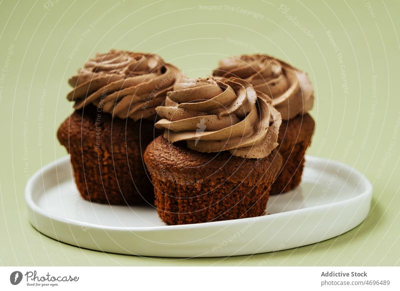 Chocolate cupcakes with frosting on plate chocolate dessert sweet confection pastry confectionery topping treat food fresh tasty delicious yummy appetizing