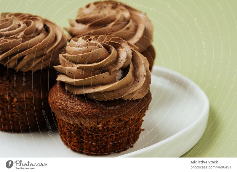 Chocolate cupcakes with frosting on plate chocolate dessert sweet confection pastry confectionery topping treat food fresh tasty delicious yummy appetizing